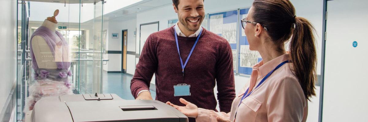 teachers chatting at printer in school hallway