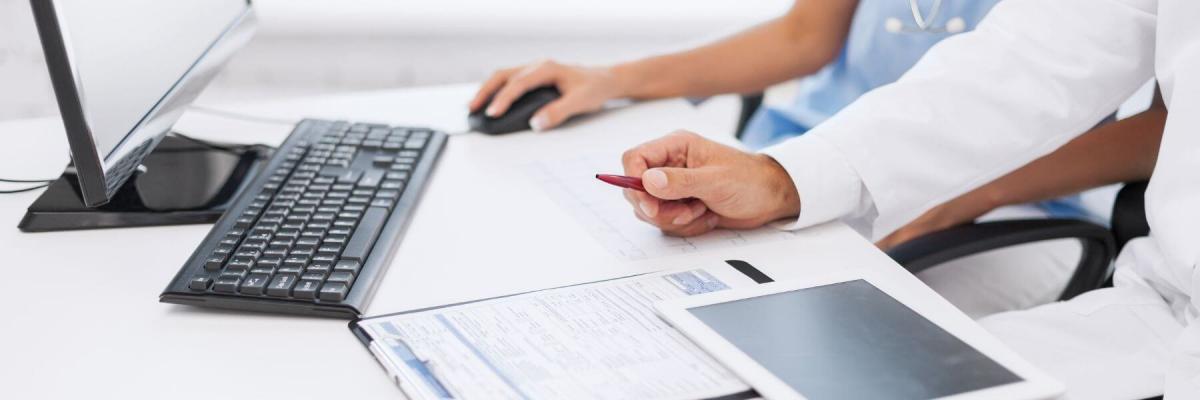 healthcare workers with paper, tablet, and desktop computer on desk